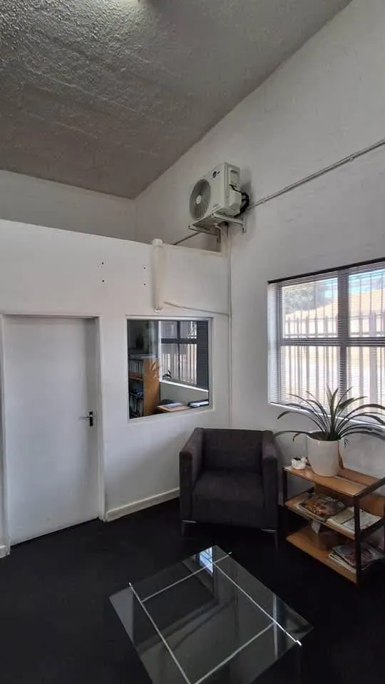 Aircon outdoor unit mounted high on a wall with pipework run along the wall